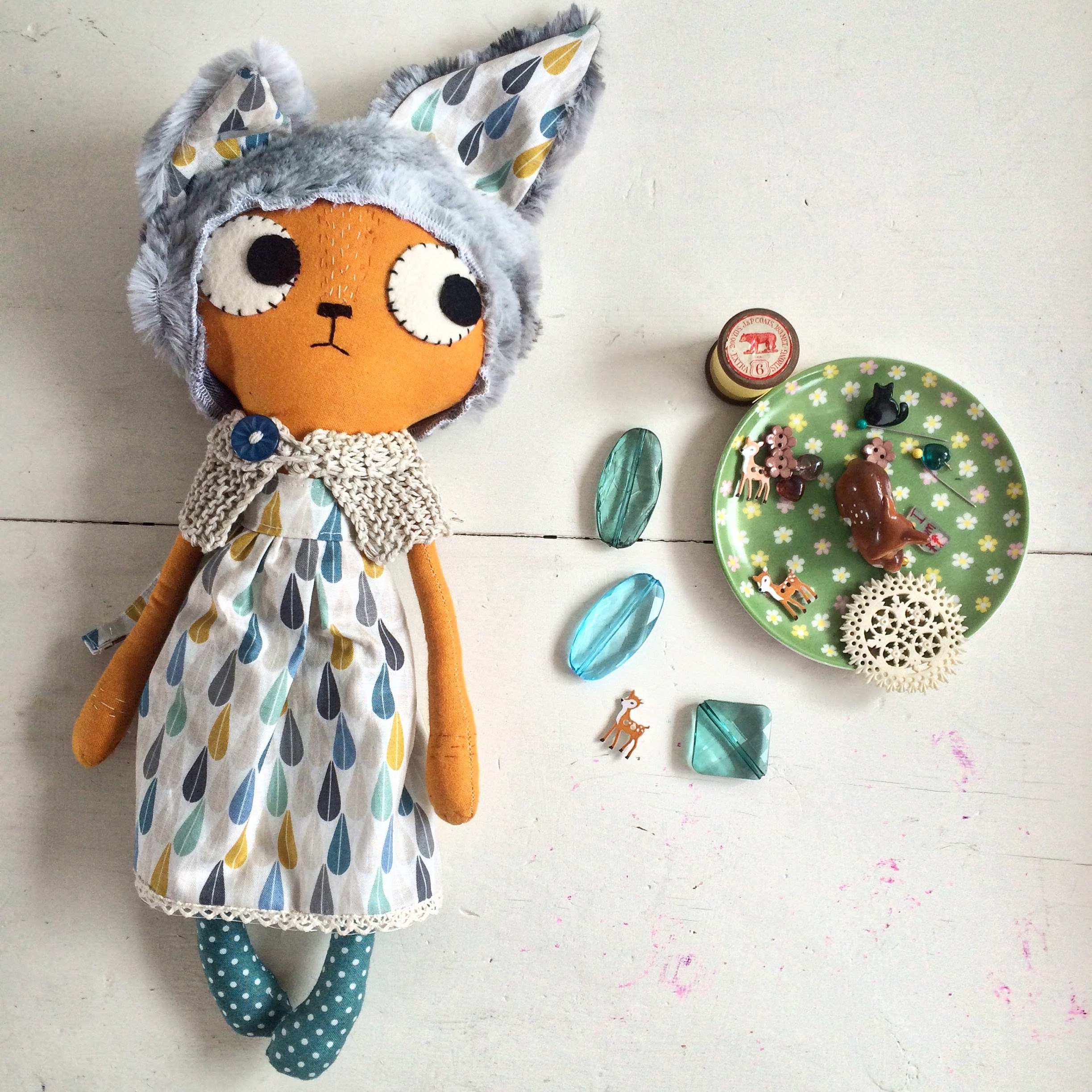 cat doll next to saucer of pins