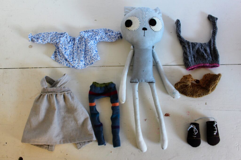 cat doll in flat lay with clothes around her