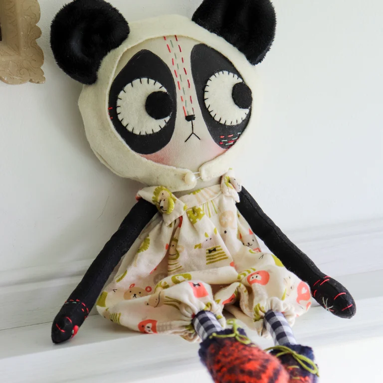 cloth panda cat doll in gauze romper sits on a shelf