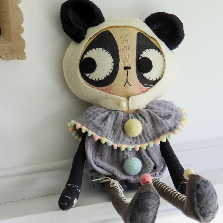 Pand cat doll in a grey romper with pastel pom poms and very long boots.
