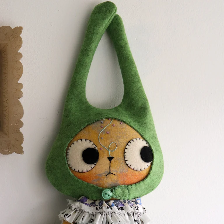 saffron coloured cat doll with a tall green hat